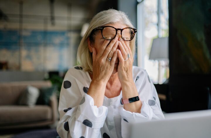 femme fatiguée par la ménopause se tenant la tête à deux mains