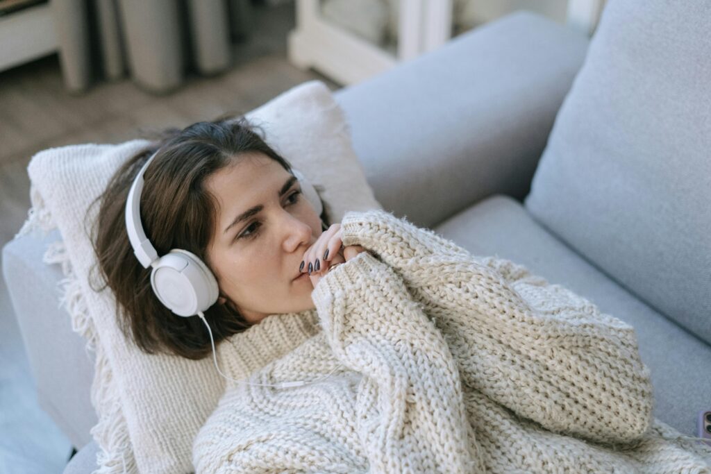 femme avec un casque audio sur son canapé