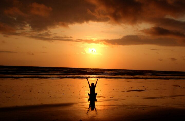 femme sur la plage devant un coucher de soleil